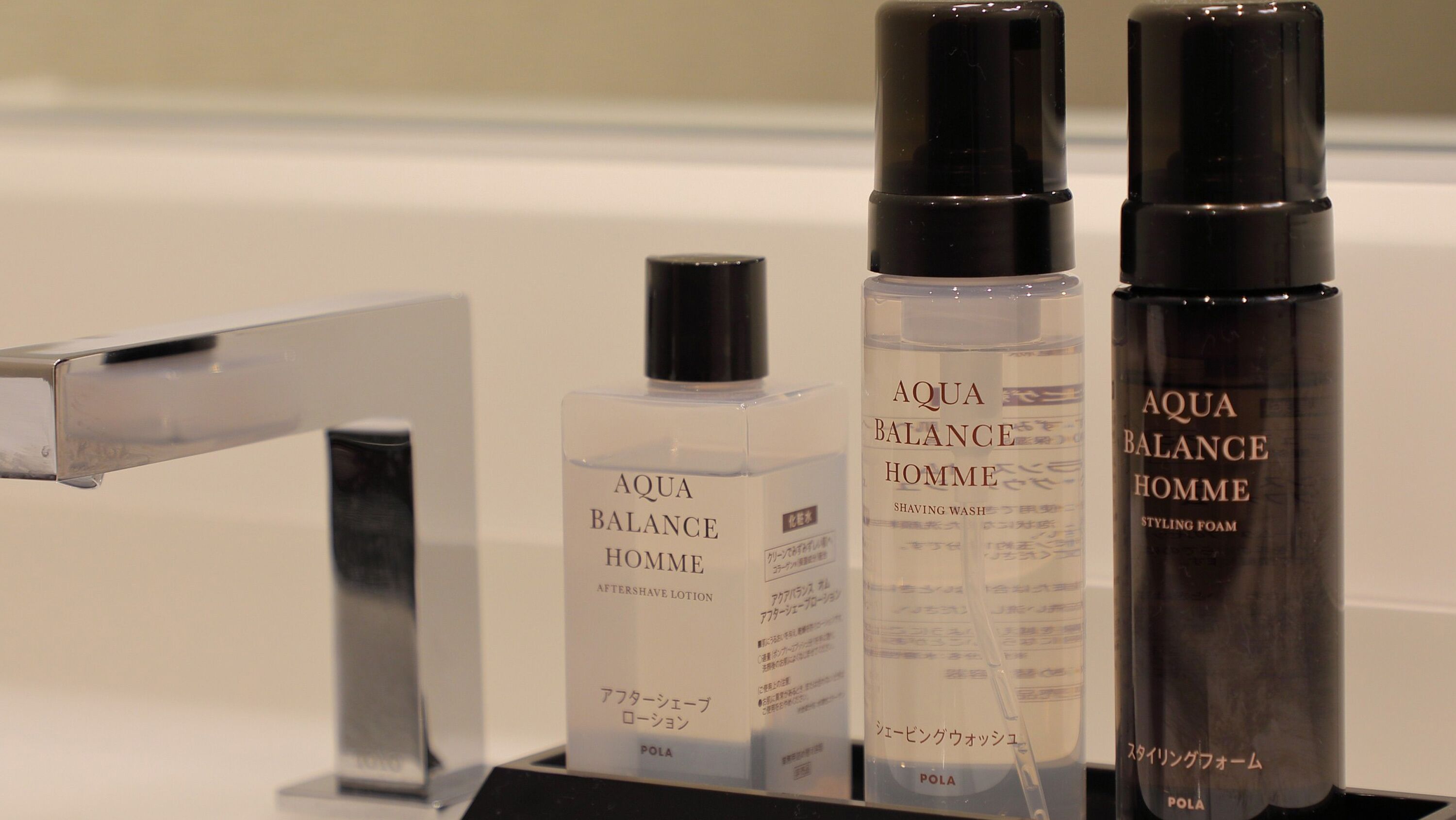 Three bottles of Aqua Balance Homme products on a display stand.