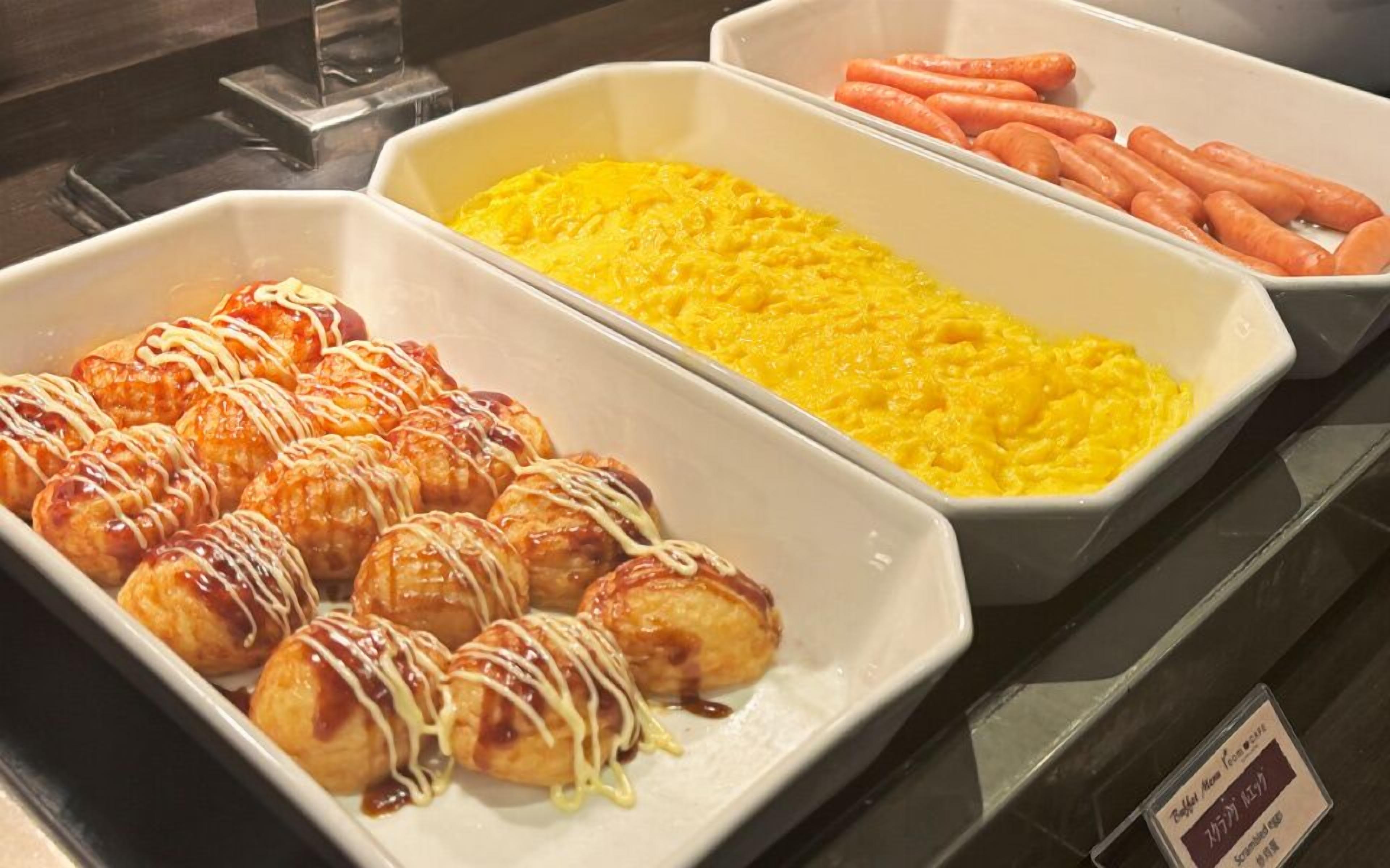 A buffet with various food items including pastries, scrambled eggs, and carrots.