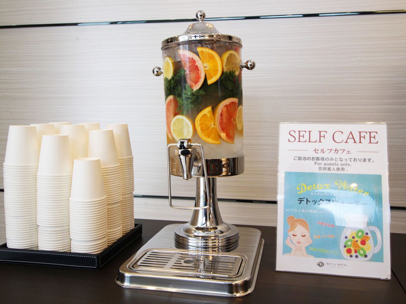 A self-service beverage dispenser with stacked cups and a sign for the self-café.