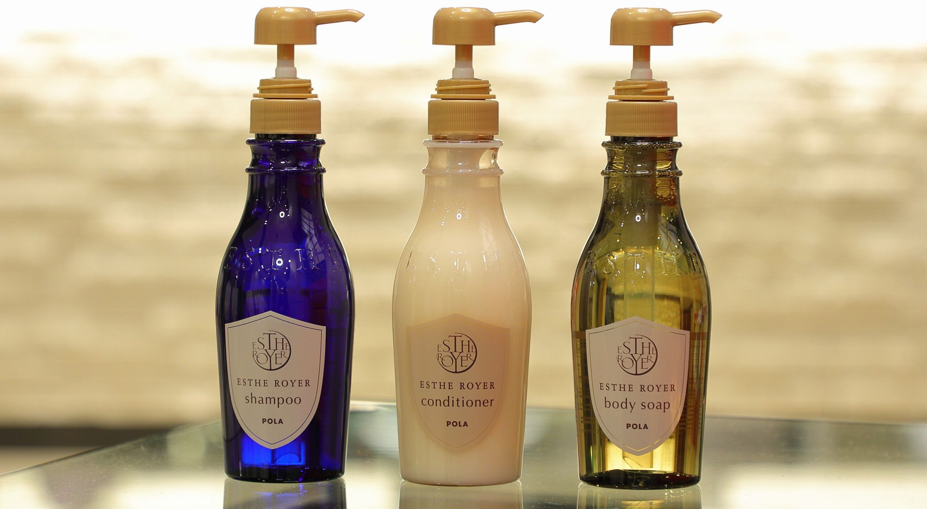 Three bottles of ESTHE ROYER products: shampoo, conditioner, and body soap, each with a pump dispenser.