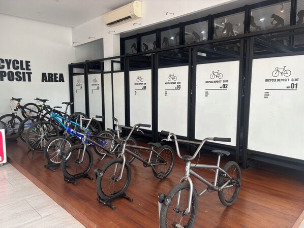 A bicycle storage area with multiple racks labeled for bicycle deposit slots. - The VELO'S hotel and BMX Pump Track (Aranyaprathet)