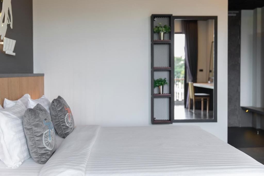 Un dormitorio moderno con una cama grande, un estante empotrado con plantas y vistas a un balcón.