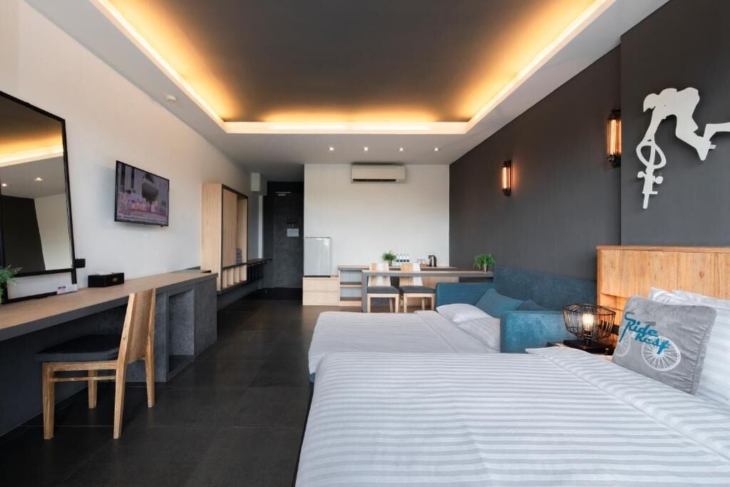 A modern hotel room with a large bed, a desk, and a seating area.