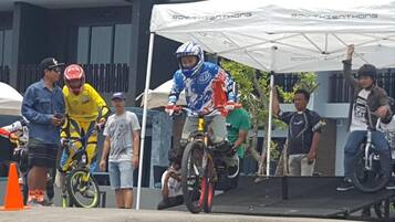 Un grupo de personas cerca de una zona de acrobacias con BMX, con una carpa con el letrero "SOY THIEN THONG" al fondo.