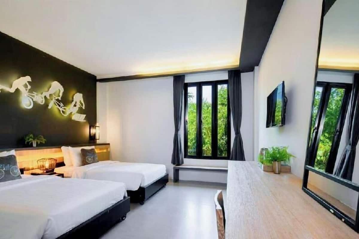 A modern hotel room with two beds, a large window with curtains, a mounted TV, and a wall-mounted light fixture.