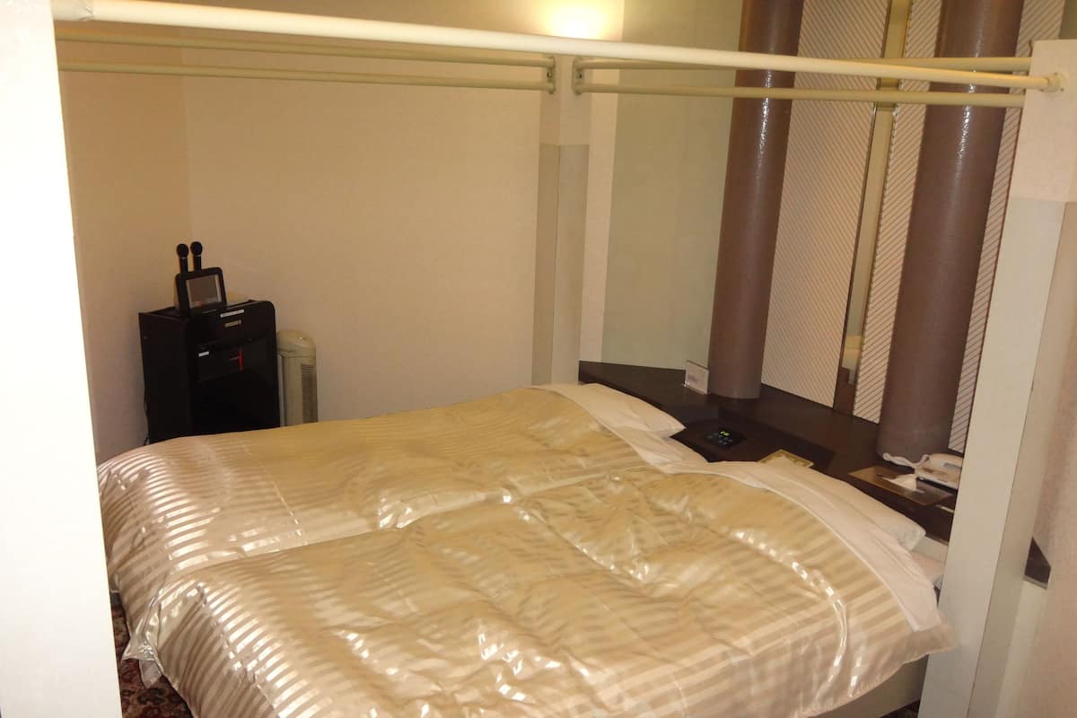 Habitació d'hotel amb llit baldaquí, una taula de nit amb una làmpada i un escriptori petit amb un telèfon.