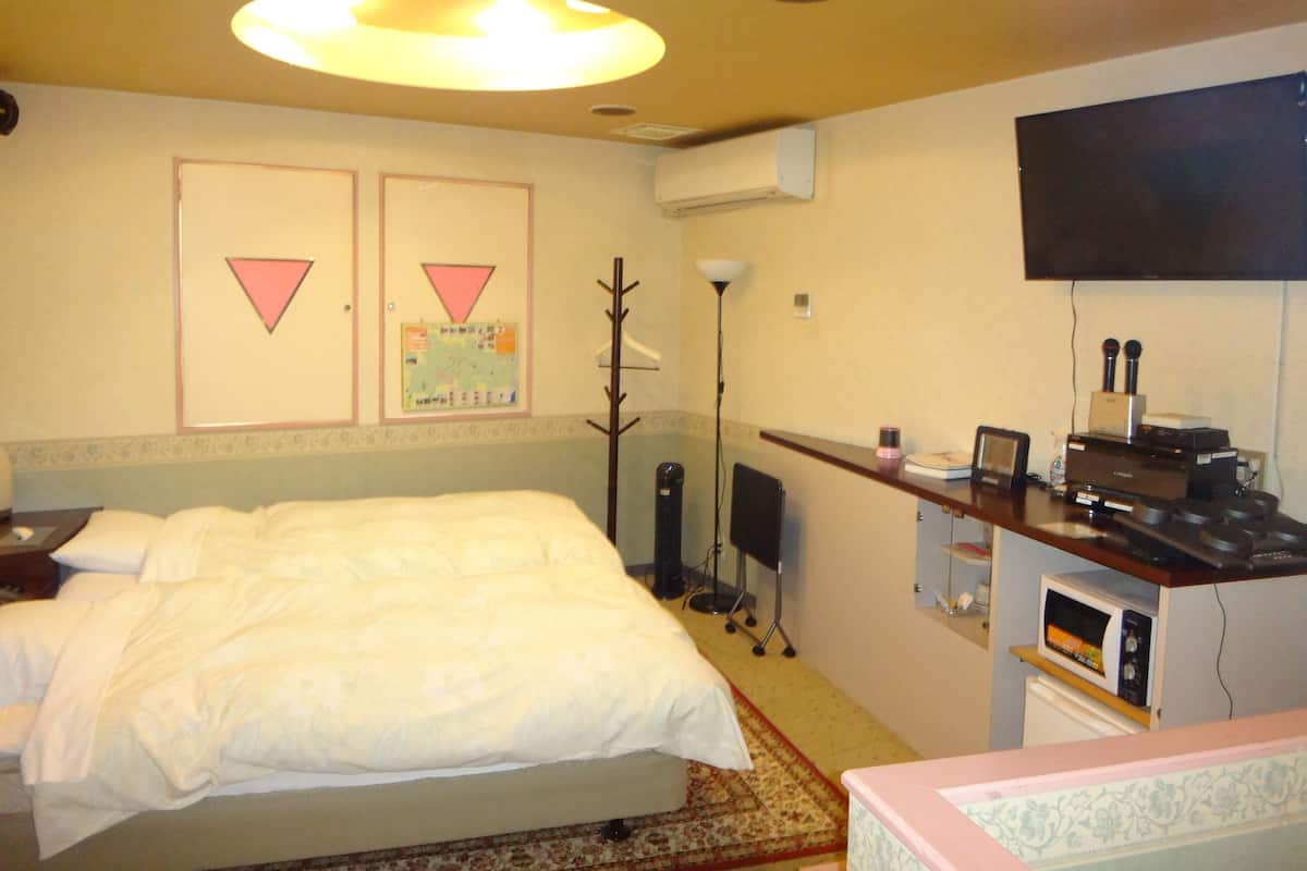 Habitació d'hotel amb llit, escriptori amb ordinador, televisió de pantalla plana i aire condicionat fixat a la paret.