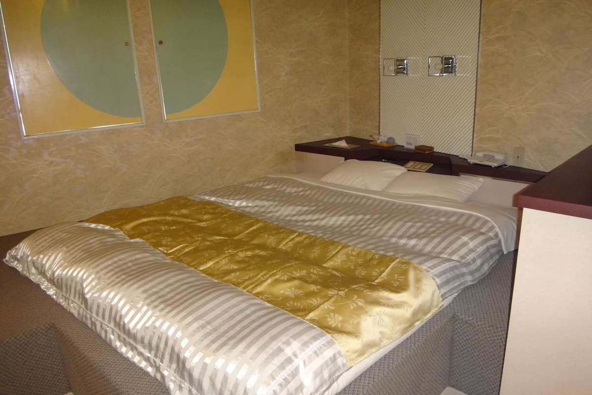 Habitació d'hotel amb llit, una vetusta, un mirall i una paret amb un disseny circular.