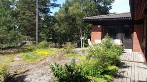 A building with a brick exterior and a tiled roof, surrounded by greenery and trees. - Kotimaailma Apartments Naantali (Naantali)