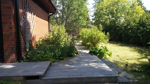 A wooden deck leading to a brick building with a metal gate. - Kotimaailma Apartments Naantali (Naantali)