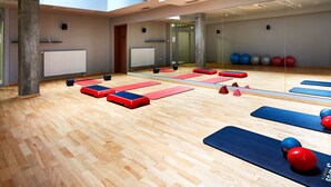 A gym with wooden floors, exercise mats, and various fitness equipment.