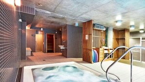 A modern spa with a hot tub, wooden accents, and tiled walls.