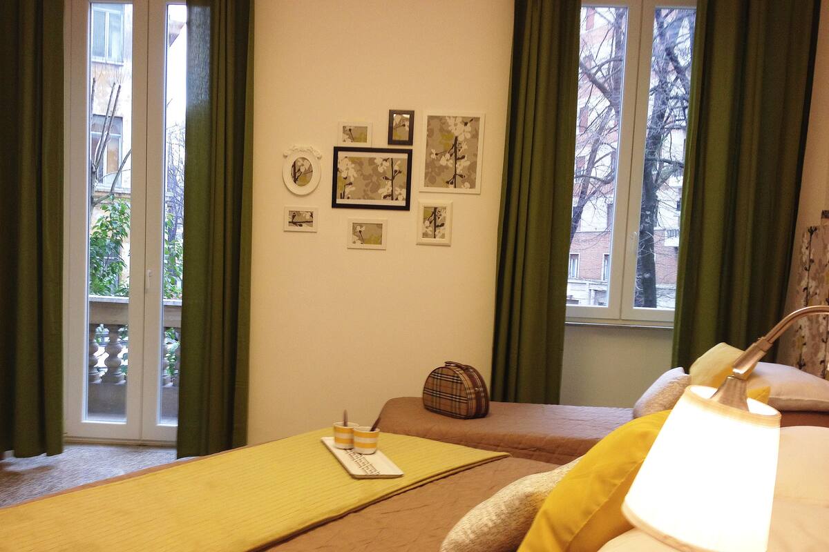 A hotel room with two beds, a window with curtains, and wall art.
