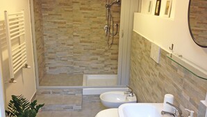 Un baño con ducha, dos lavamanos, inodoro y espejo.