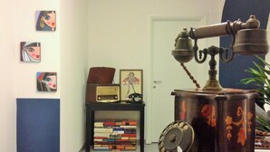Una habitación con un teléfono antiguo, una estantería y una puerta al fondo.