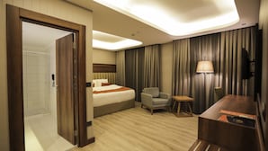 Une chambre d’hôtel avec un lit, une chaise, une petite table, une lampe et un téléviseur.