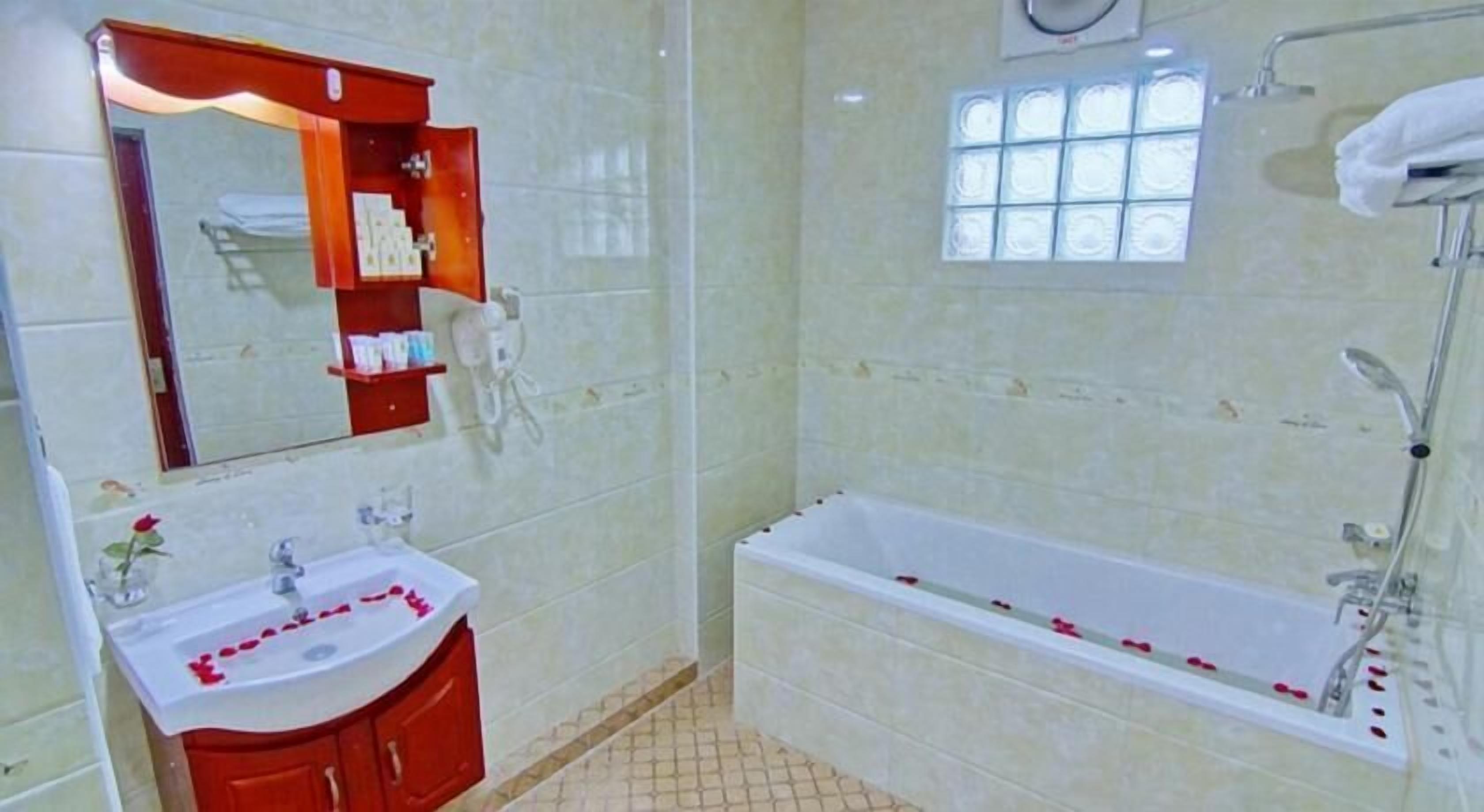 A bathroom with a sink, mirror, and bathtub.
