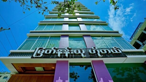 Um edifício moderno com uma placa que diz "Boss Hotel" em inglês e outro idioma.