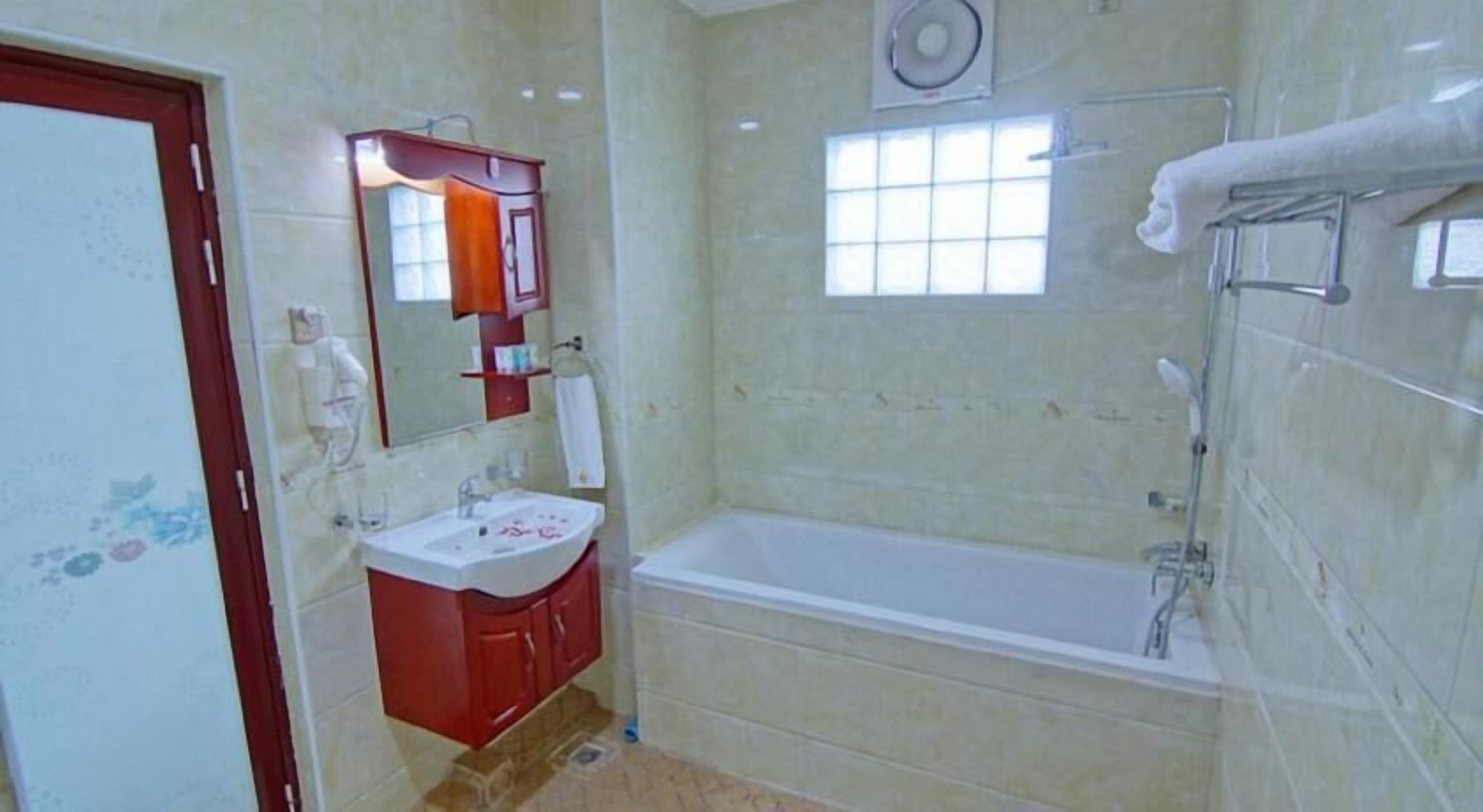 A bathroom with a bathtub, a sink, and a mirror.