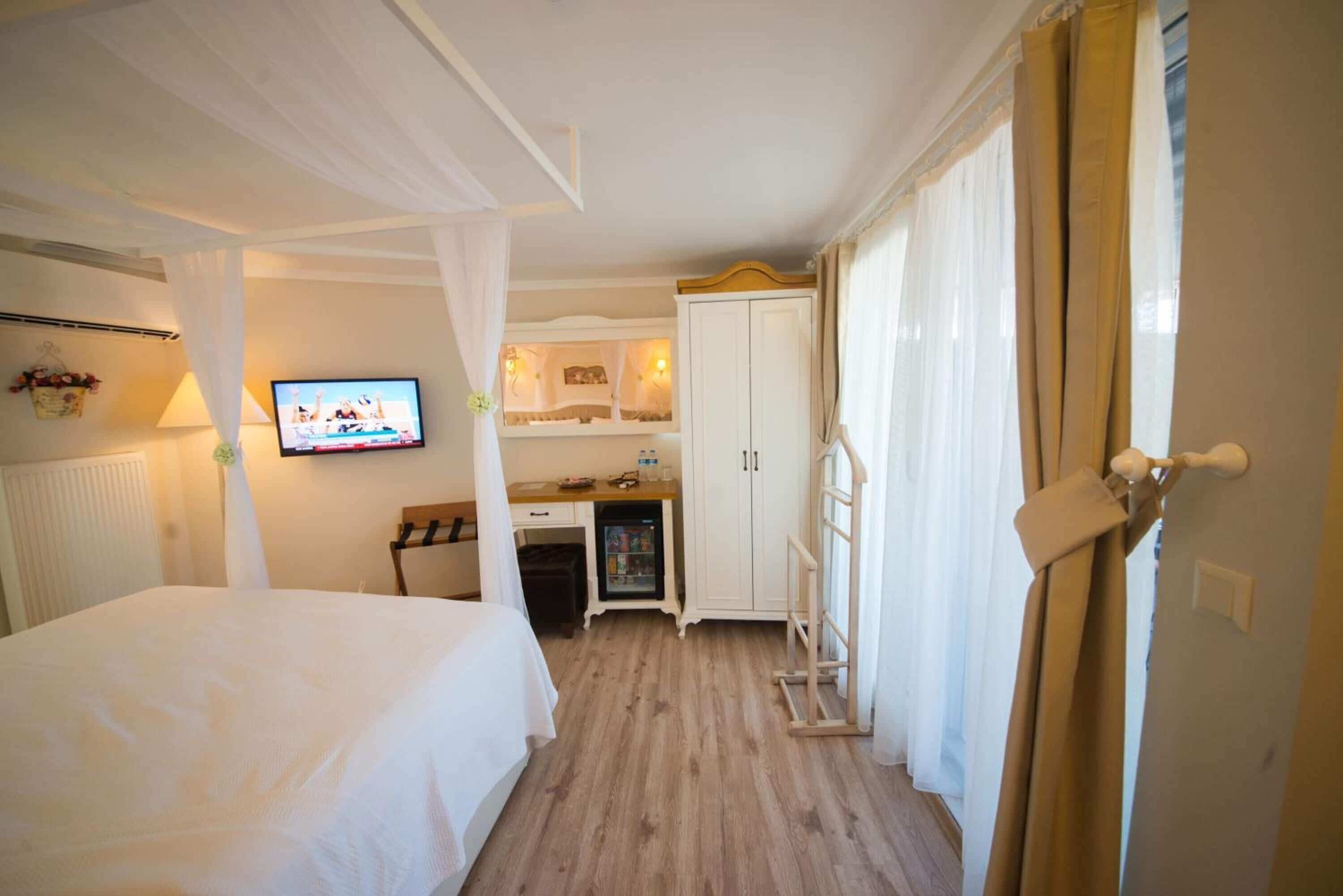 A bedroom with a bed, a television, a small kitchenette, and a wardrobe.