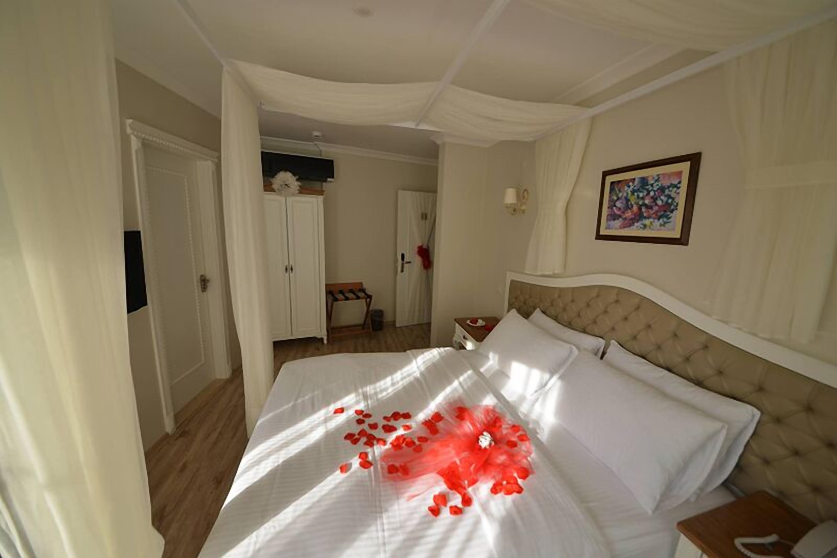 Una habitación de hotel con una cama grande, un cabecero, una mesita de noche y un cuadro colgado en la pared.