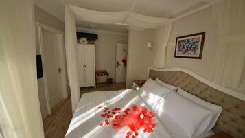 Una habitación de hotel con una cama grande, un cabecero, una mesita de noche y un cuadro colgado en la pared.