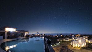 A nighttime resort with a swimming pool, beachfront villas, and a starry sky.