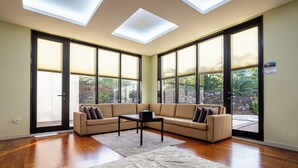 A spacious living room with a sectional sofa, a coffee table, and a large window with a view of greenery.