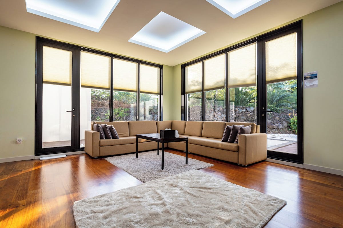 A spacious living room with a sectional sofa, a coffee table, and a large window with a view of greenery.
