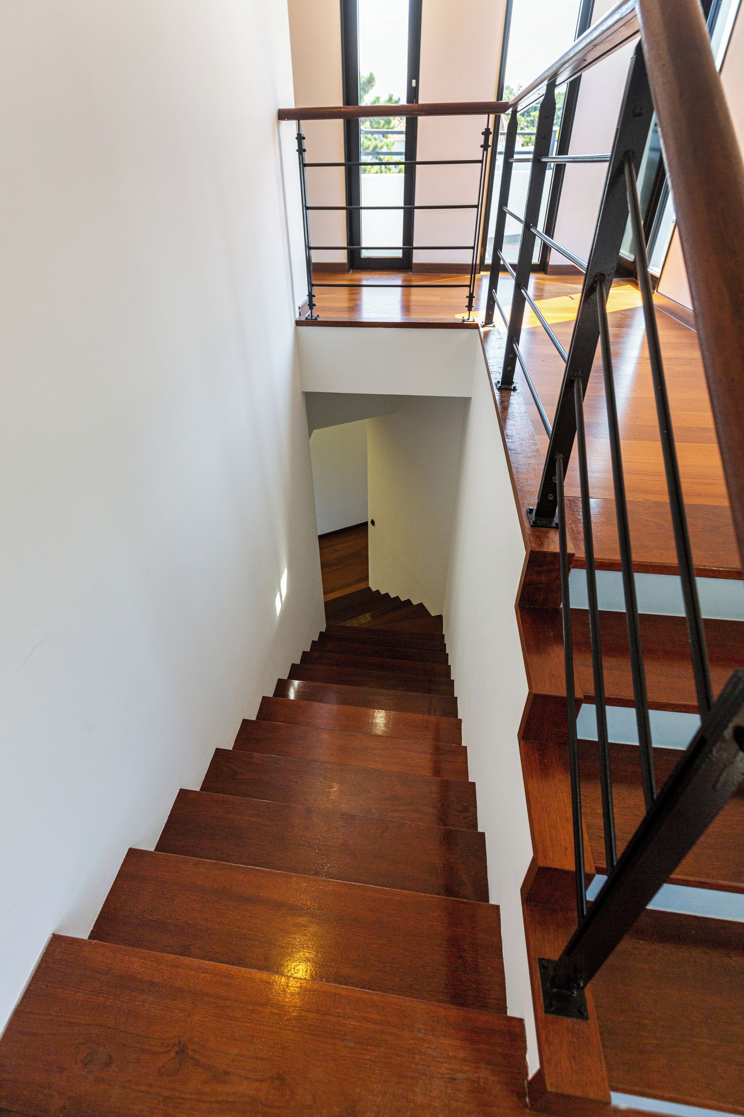 A wooden staircase with a metal railing leading to an upper level.