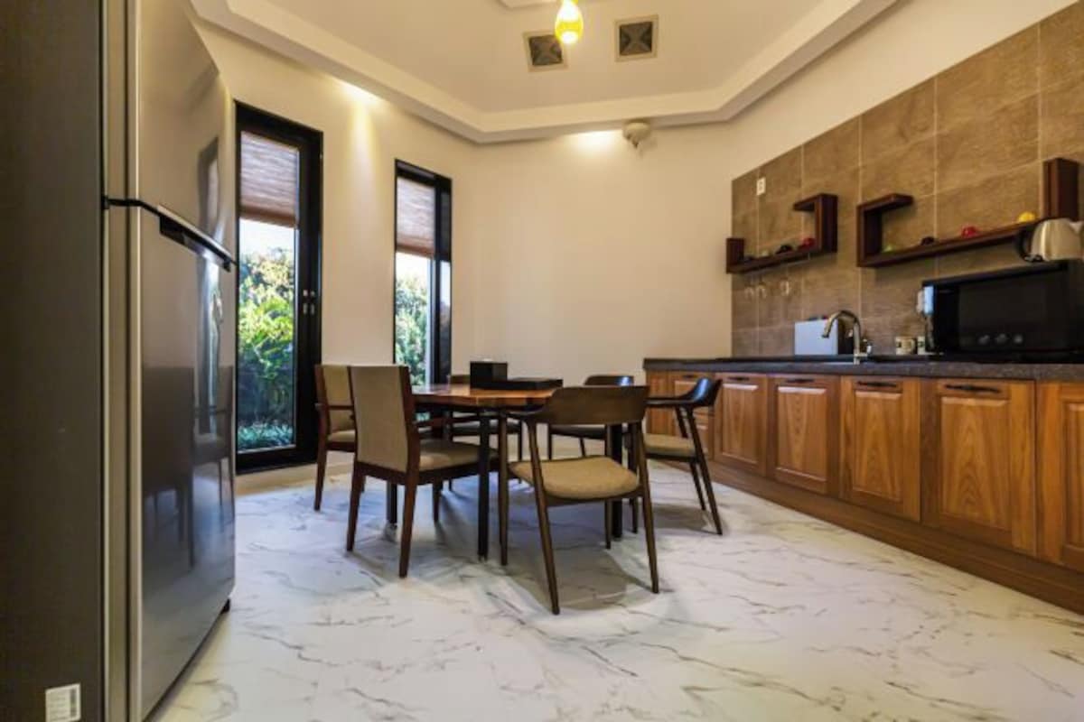 Una cocina moderna con una mesa de comedor y sillas, un refrigerador y armarios de madera.
