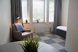 Une chambre moderne et compacte, comprenant un canapé, une petite table, une plante en pot et un lit.