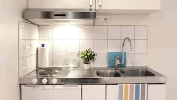 Uma cozinha moderna com uma pia de aço inoxidável, um exaustor e uma planta em vaso.