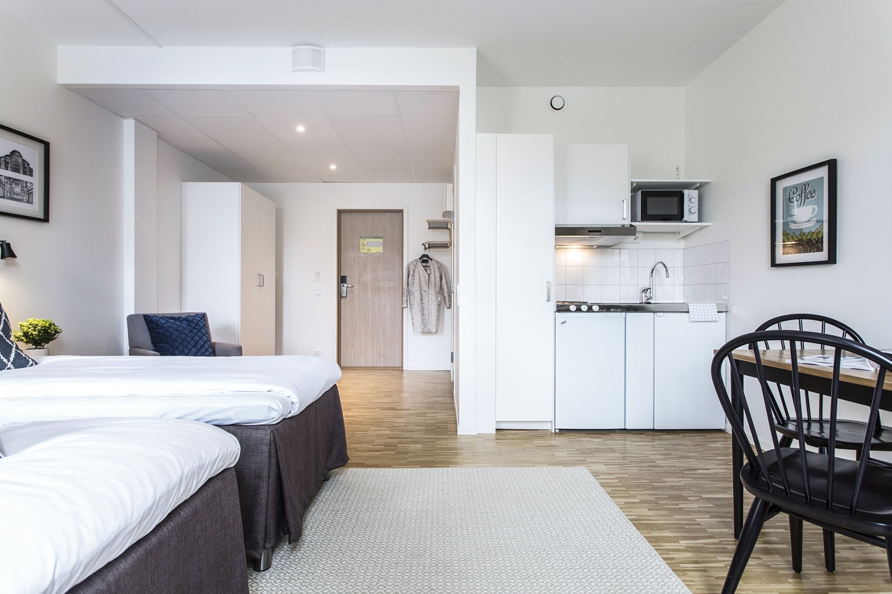Een kleine hotelkamer met een bed, een kitchenette, een eethoek en een badkamer.