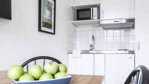 Une cuisine moderne avec des armoires blanches, un four à micro-ondes et une hotte de cuisinière en acier inoxydable.