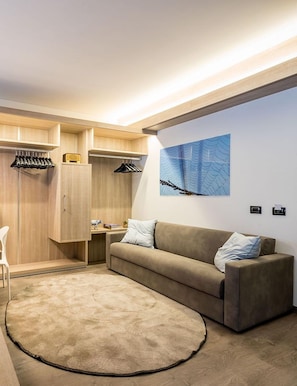 Ein modernes Zimmer mit einem beigen Sofa, einem runden Teppich, einem Holzschrank und einem Wandbild.