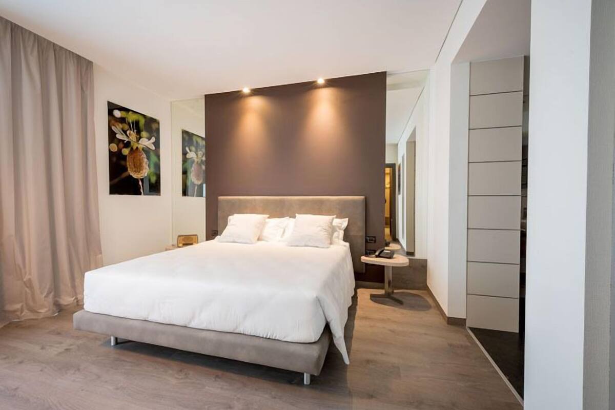 A modern bedroom with a large bed, a bedside table, and a nightstand.