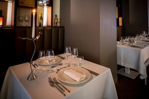 Un restaurante con mesas dispuestas para comer, incluyendo platos, cubiertos y copas de vino.