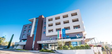 Un moderno edificio de hotel con varios pisos, grandes ventanales y una entrada destacada.