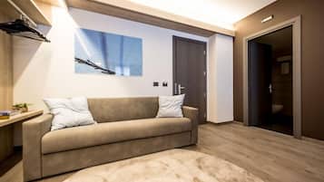 A modern living room with a beige sofa, a large abstract painting, and a wooden floor.