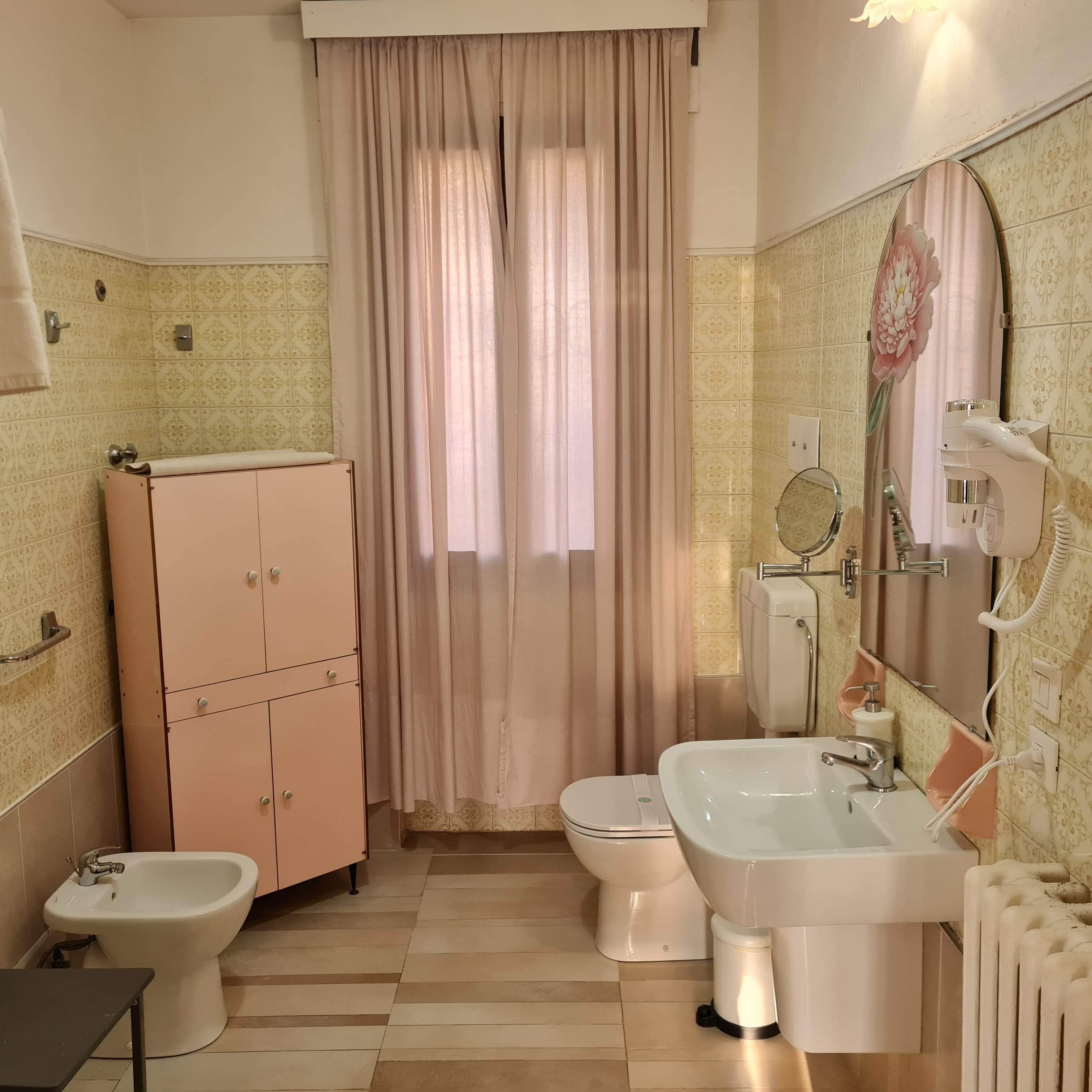Un baño con bidé, inodoro, lavabo y un armario.