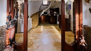 A grand entrance with a marble floor, a wooden door with a mirror, and a chandelier.