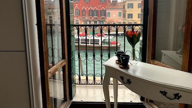 A balcony with a view of Venice's colorful buildings and a canal.