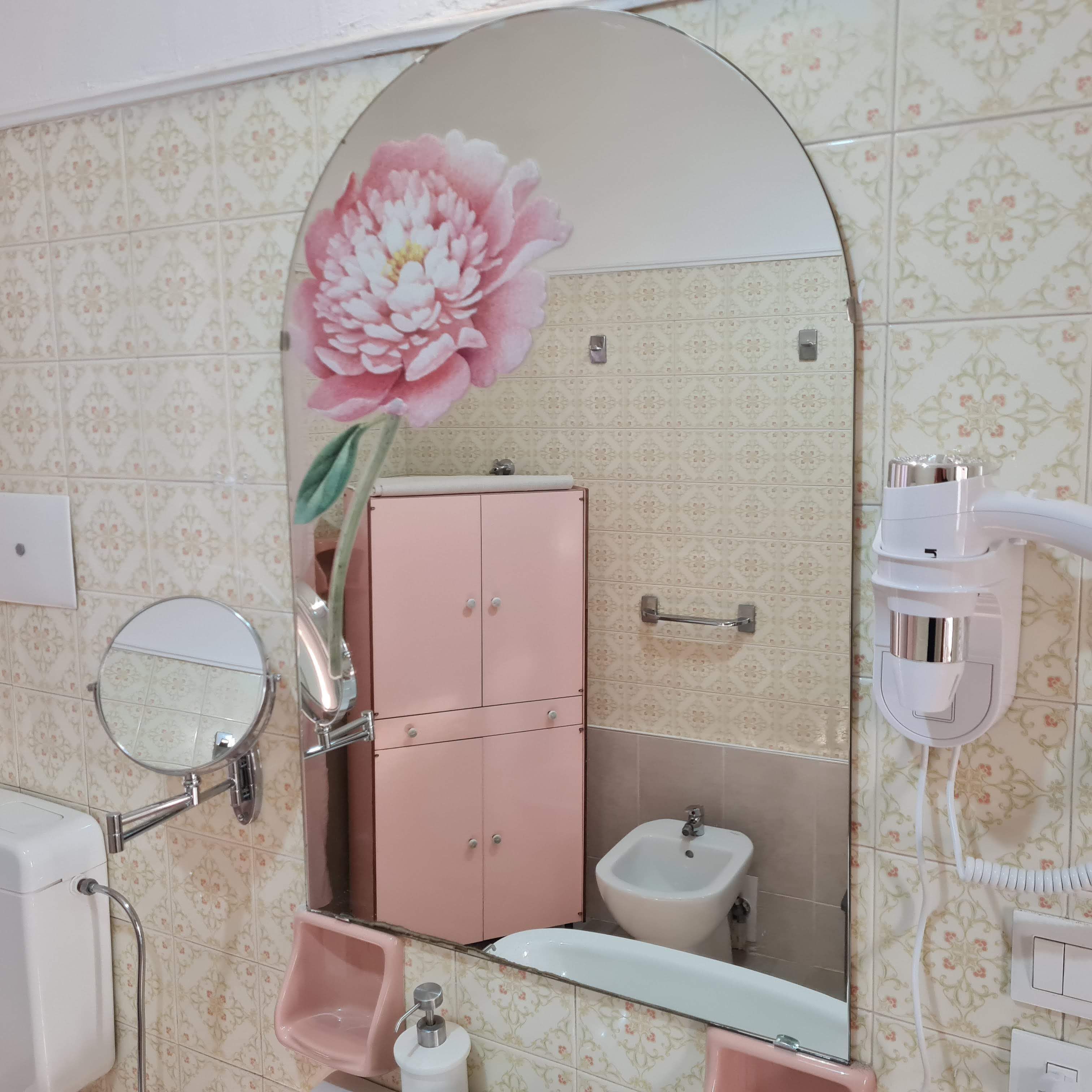Un baño con un mueble rosa, un lavabo, un espejo y un inodoro.