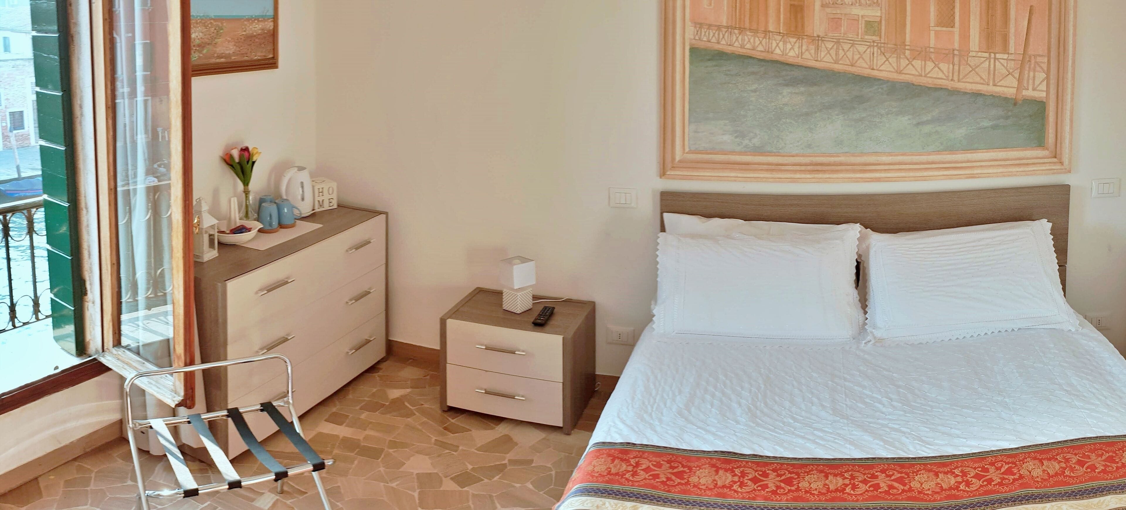 Un dormitorio ordenado con cama, mesita de noche y una silla.