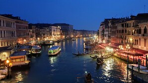 A canal with boats, buildings, and a night-time view.