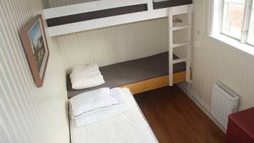 A bunk bed room with a window, a radiator, and a red dresser.