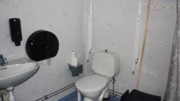 Un baño con lavamanos, inodoro y un cubo de basura negro.
