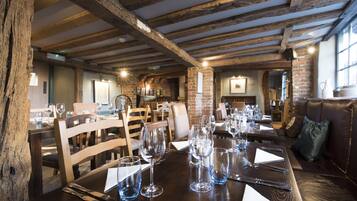 A restaurant with exposed wooden beams, brick walls, and a cozy seating area with leather couches.