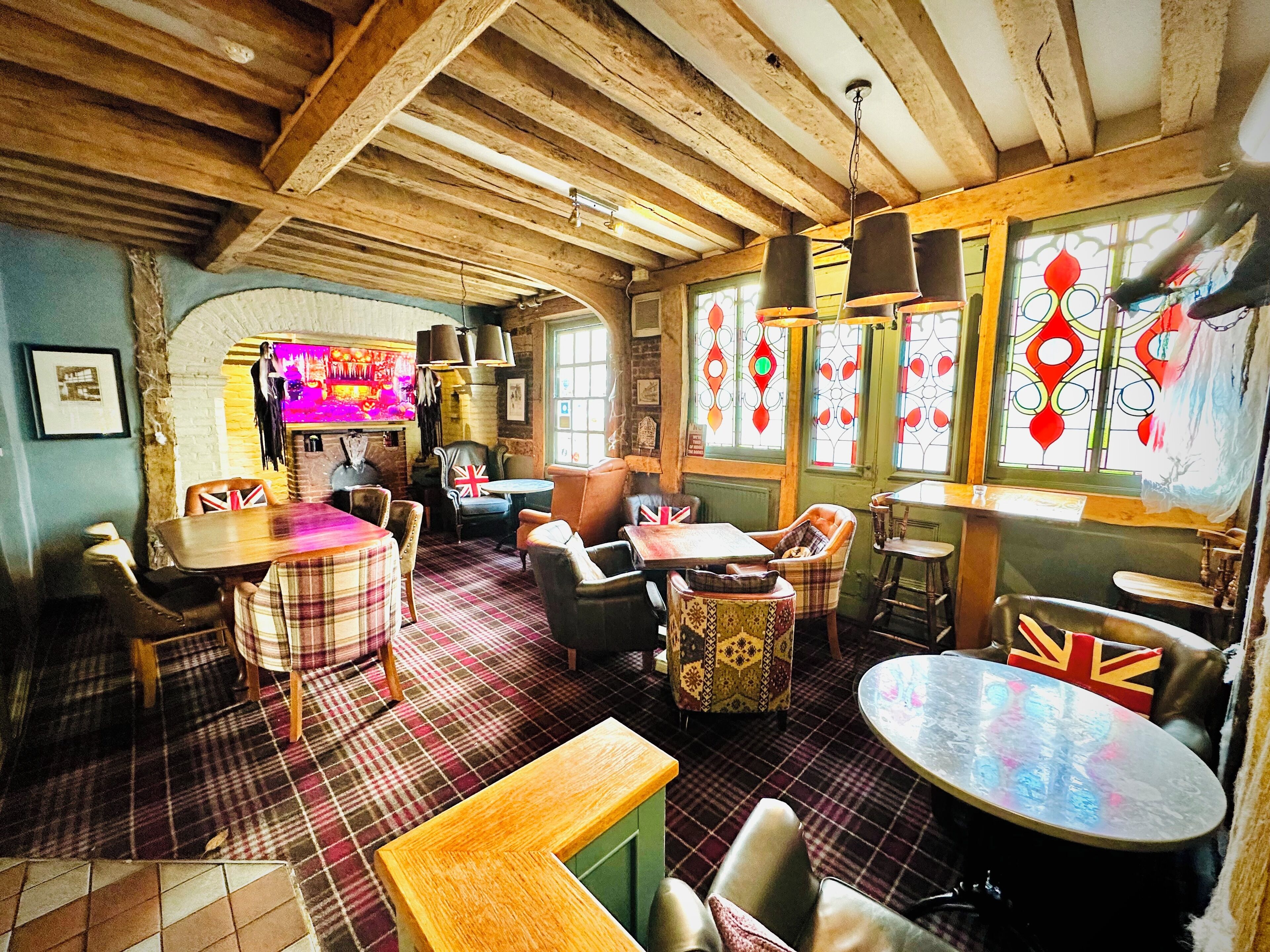 A cozy pub with wooden beams, plaid flooring, and traditional British decor.